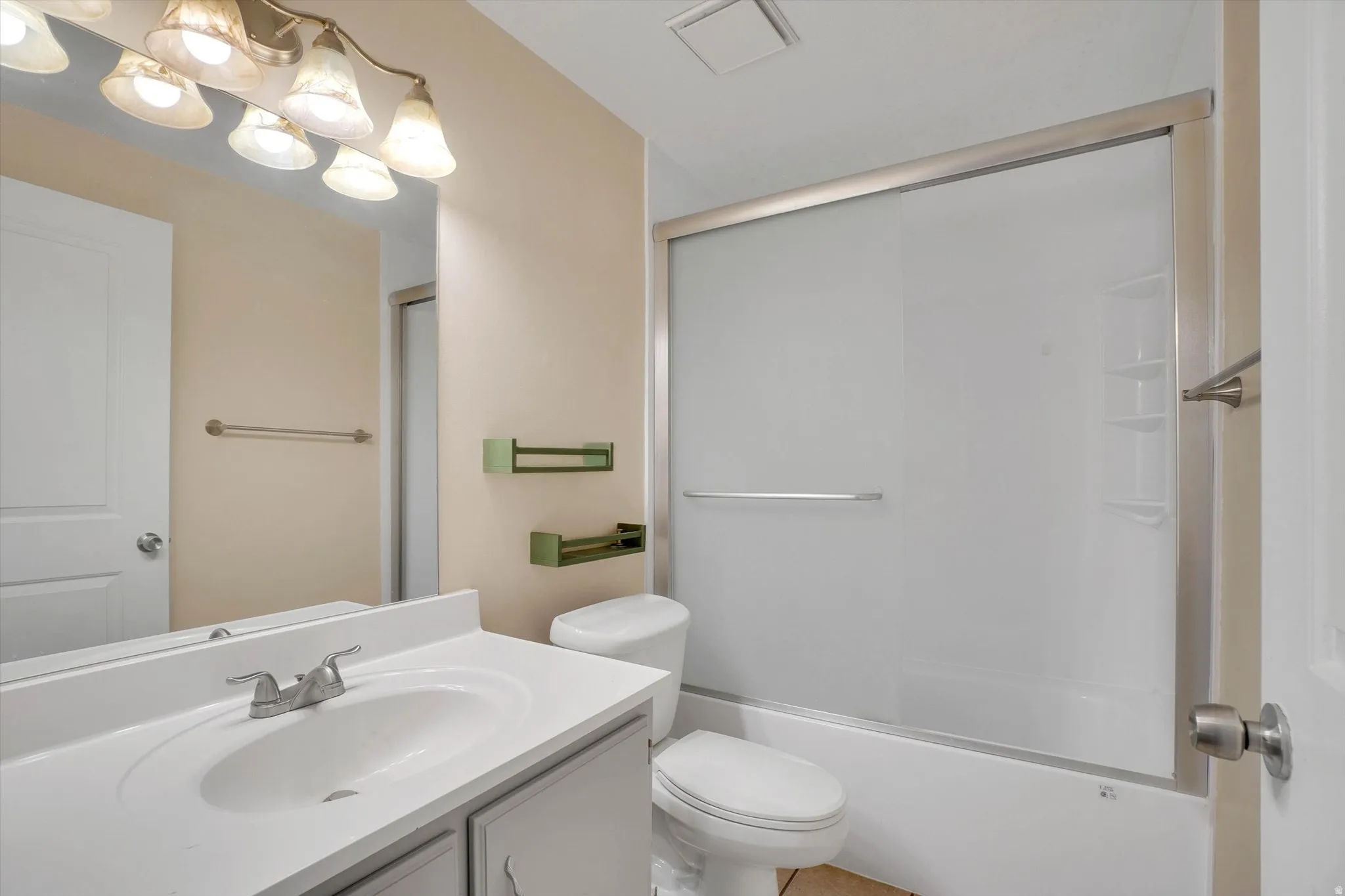 Vanity with integrated sink and chrome fixtures, framed mirror, and a sliding glass shower enclosure
