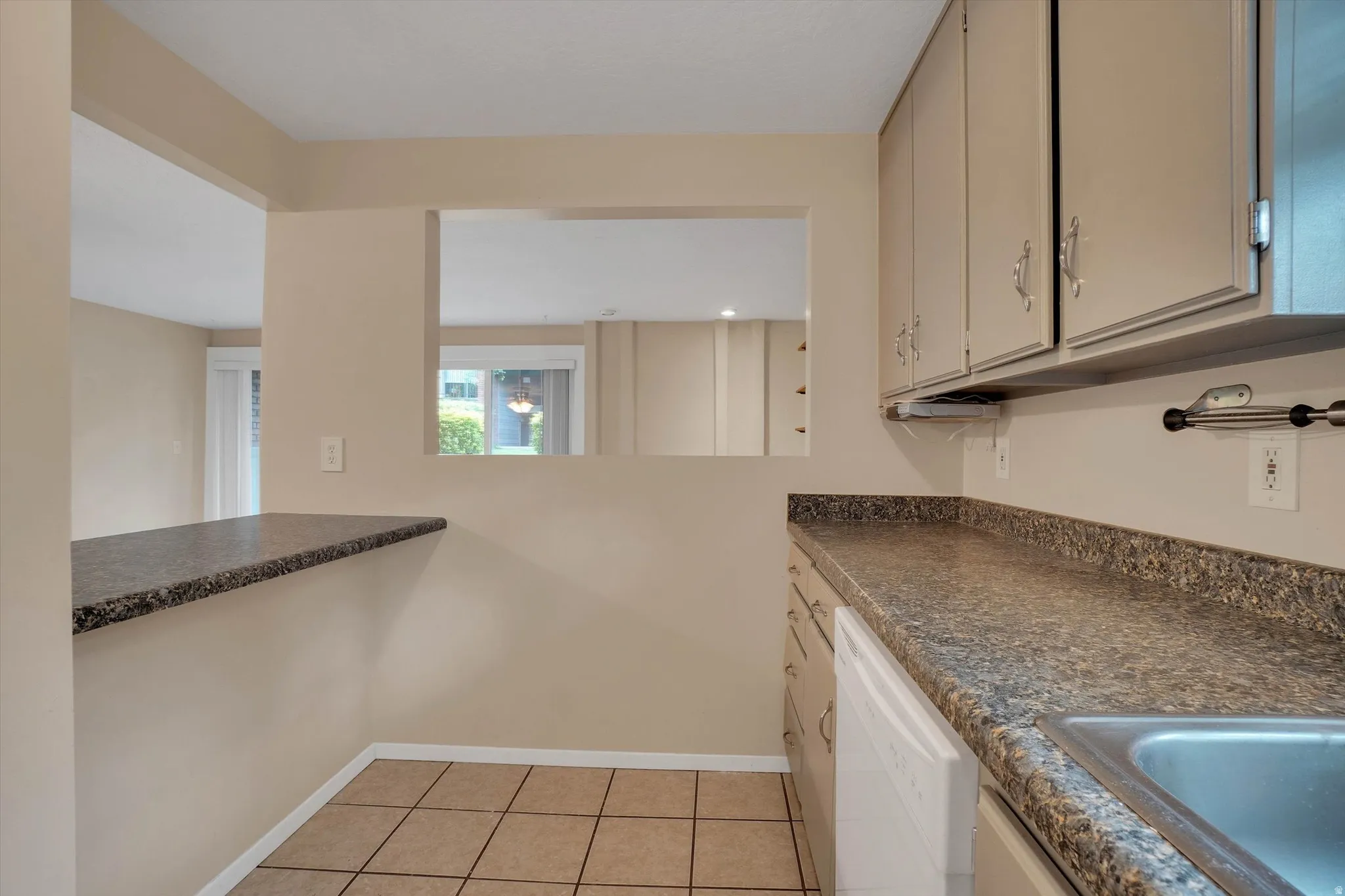 Kitchen featuring tile flooring, a pass-through window, and a built-in dishwasher