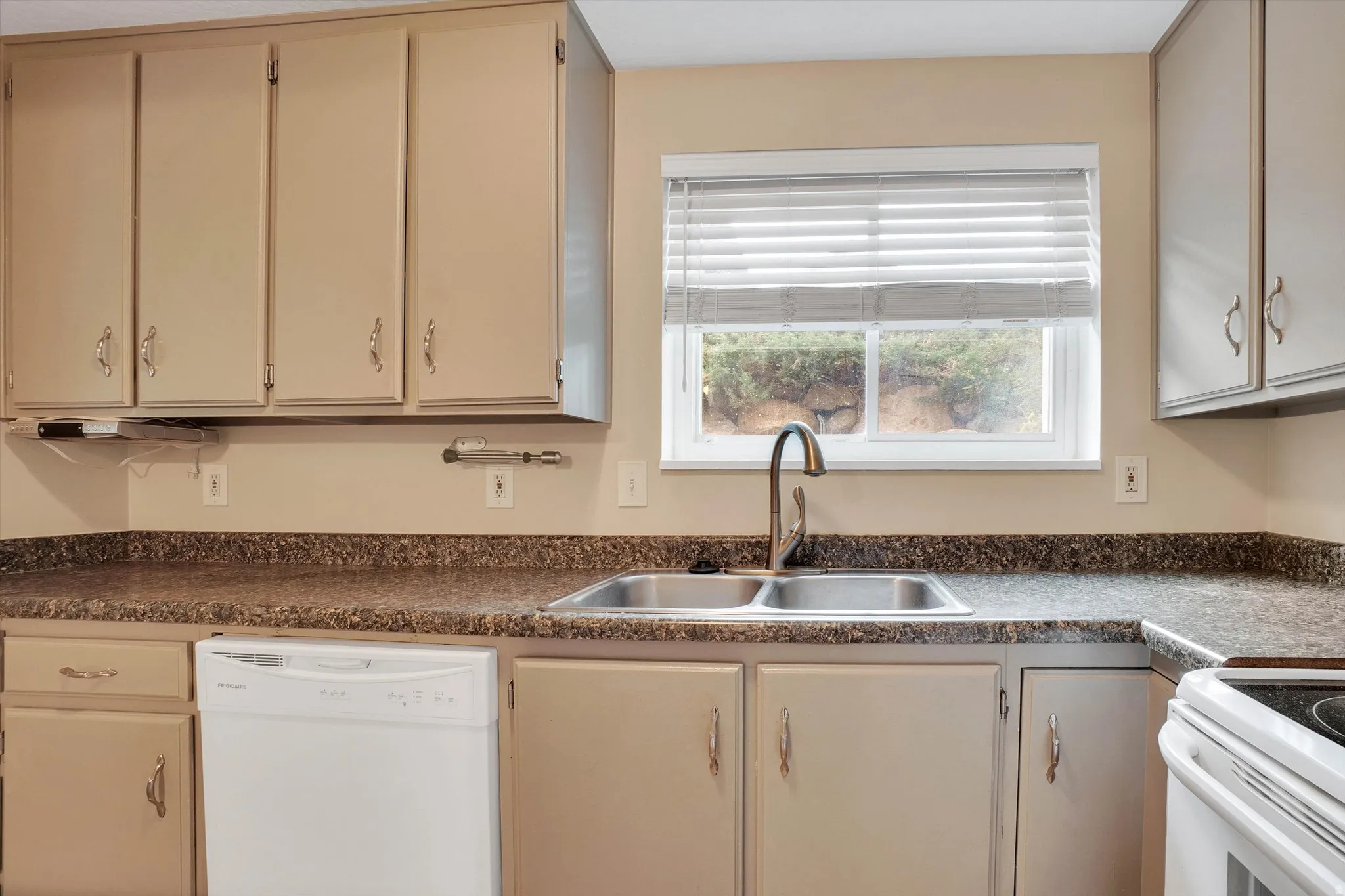Kitchen featuring a double basin stainless steel sink, light-toned cabinetry, laminate countertops, and a white dishwasher