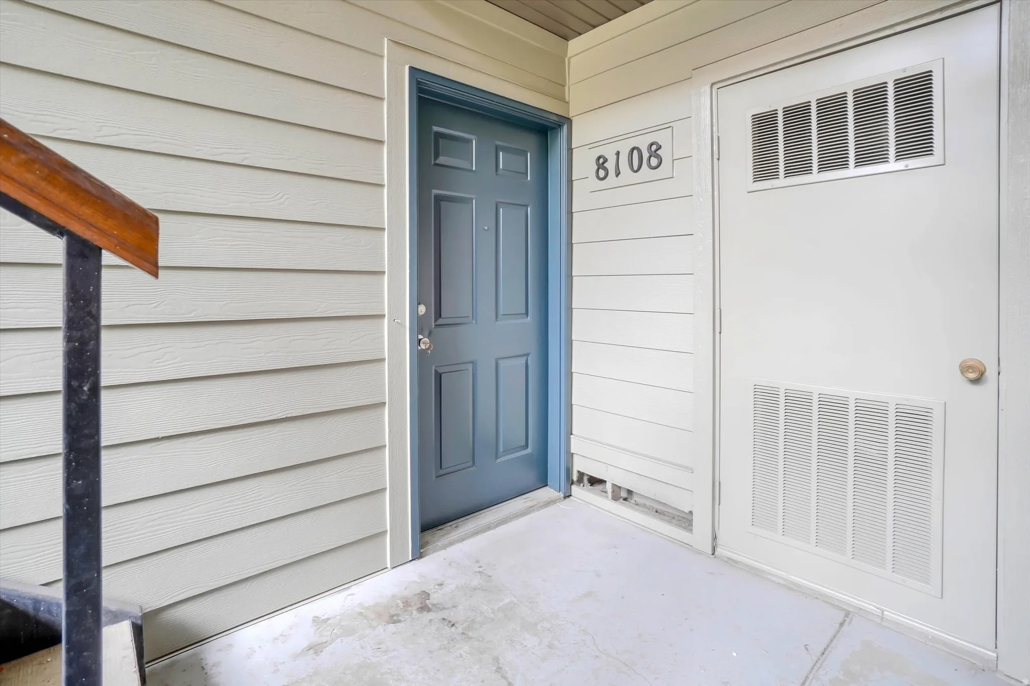 Horizontal siding exterior with a paneled entry door and concrete flooring