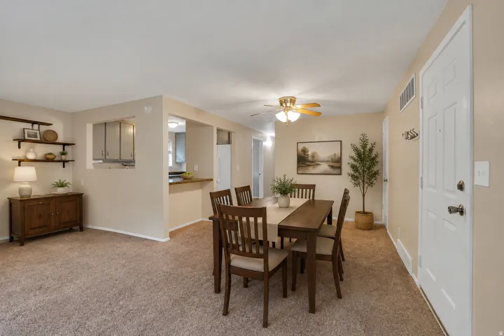 Open concept layout with carpeting, a pass-through window, and a ceiling fan