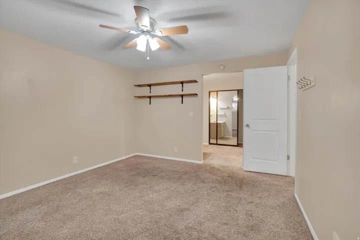Master bedroom has Carpeted room with a ceiling fan, neutral wall paint, and built-in shelving