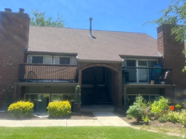 Brick exterior with a shingle roof and two balconies featuring metal railings