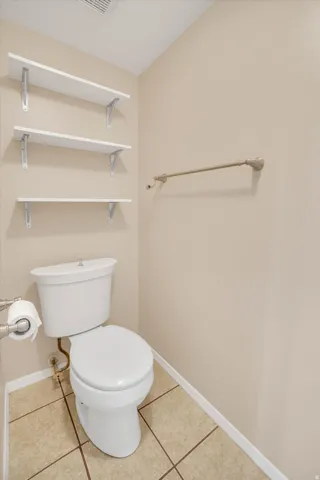Built-in shelving, ceramic tile flooring, and a towel bar in master bathroom