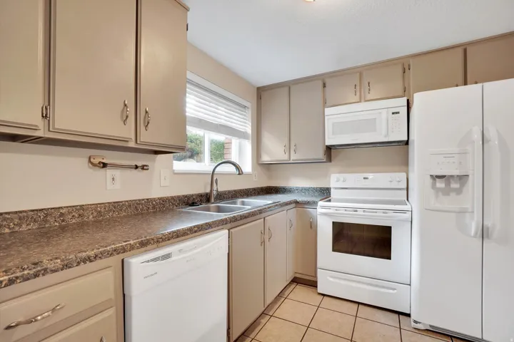 Kitchen featuring neutral-toned cabinetry, laminate countertops, a double basin stainless steel sink, and tile flooring