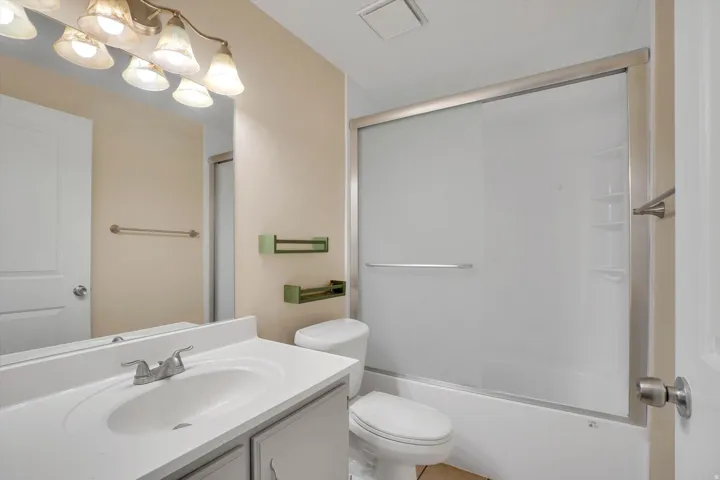 Vanity with integrated sink and chrome fixtures, framed mirror, and a sliding glass shower enclosure