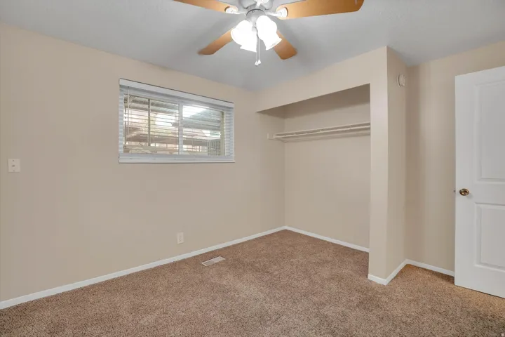 2 nd bedroom includes Neutral wall color, carpeted flooring, window with horizontal blinds, built-in closet, and ceiling fan with integrated lighting