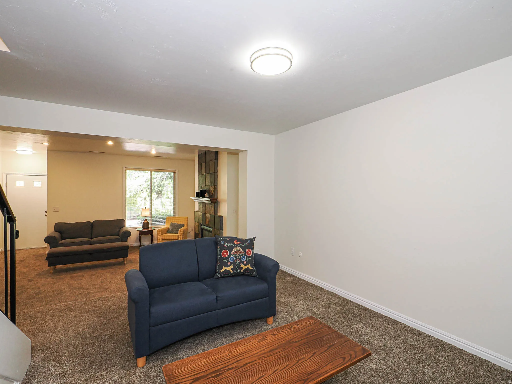 Carpeted living area with white walls and a contemporary flush-mount ceiling light