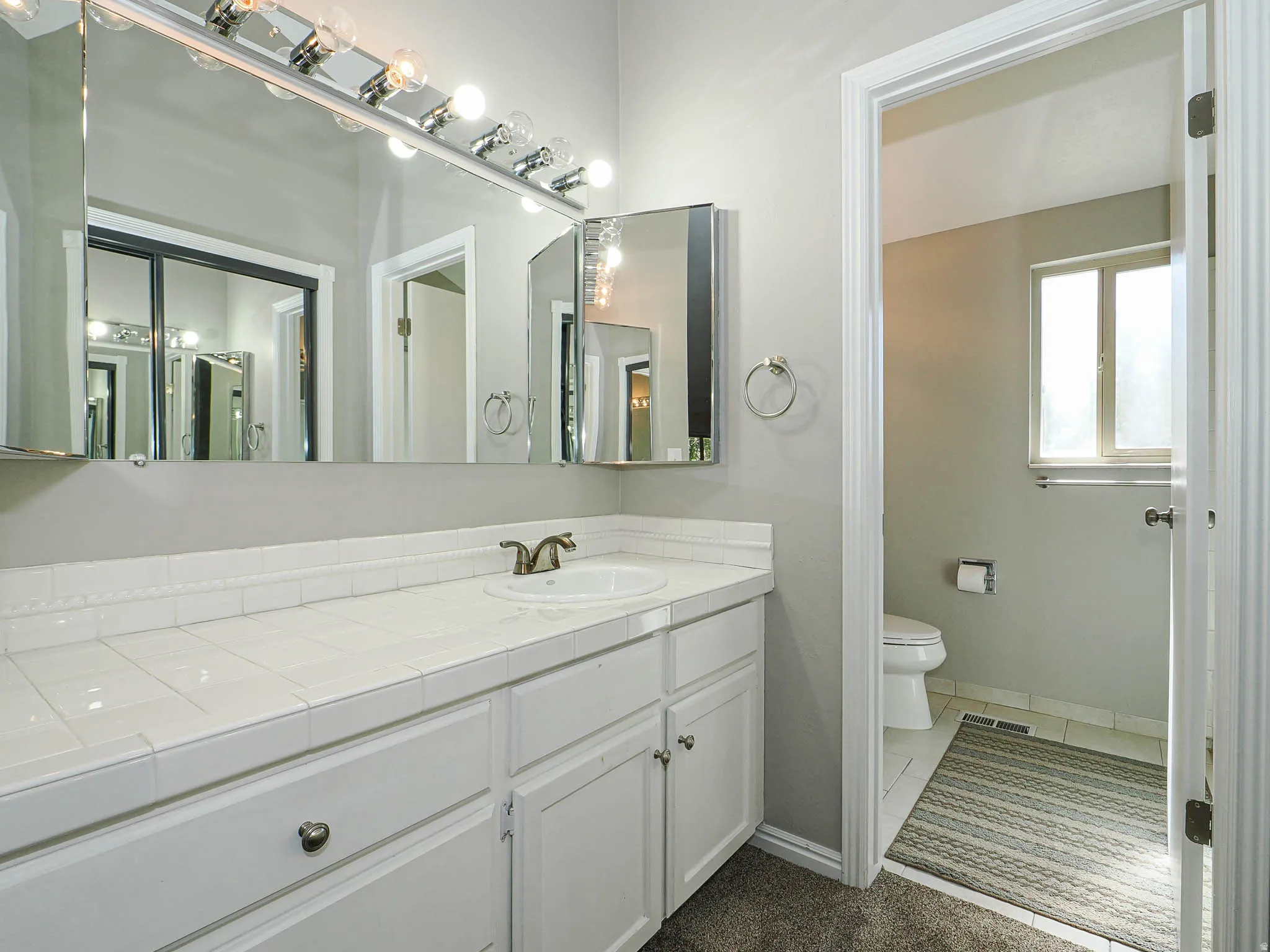 Bathroom vanity with white tiled countertop and integrated sink