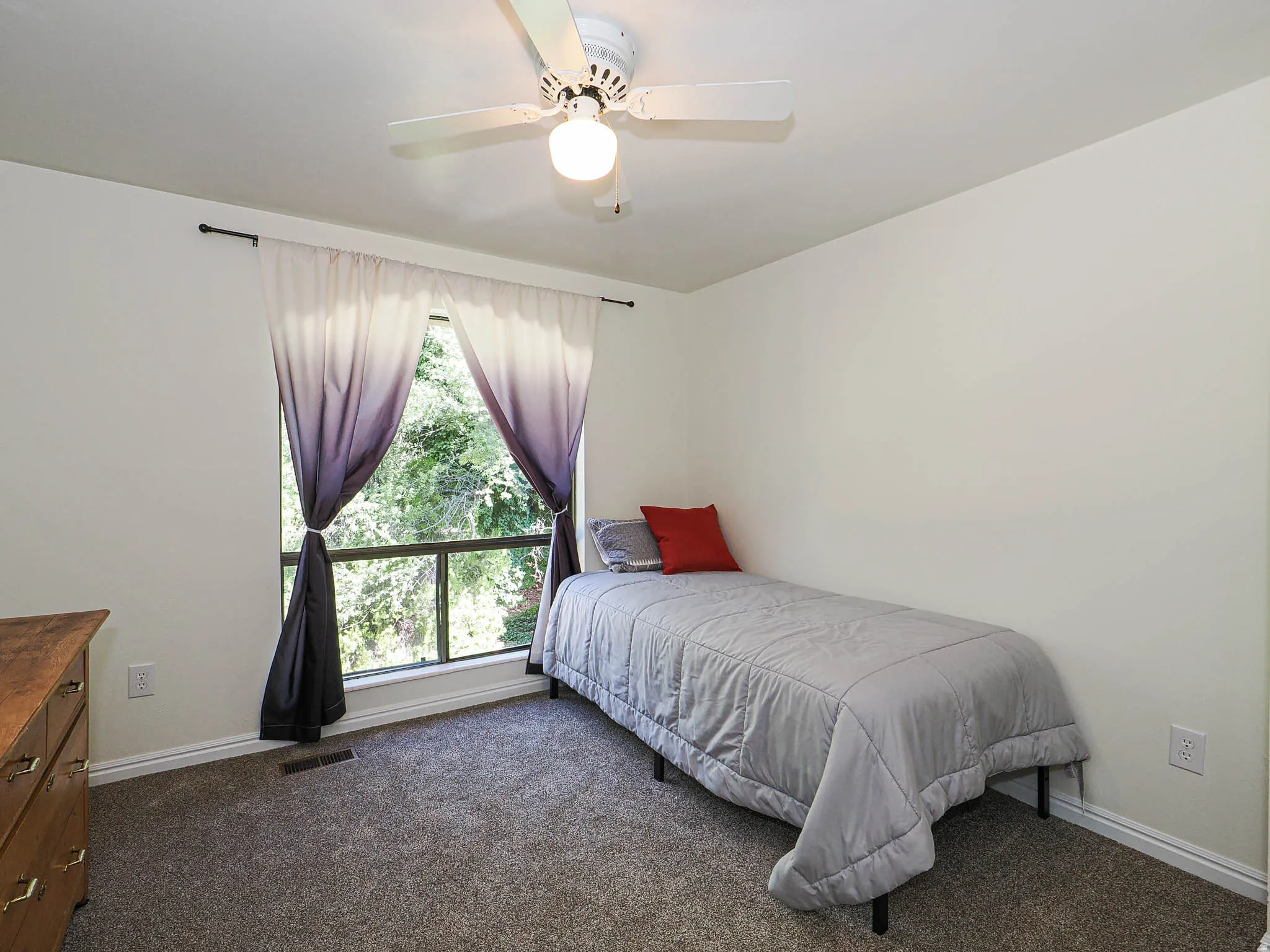 Carpeted room featuring a ceiling fan with integrated lighting, a large window, and white baseboards