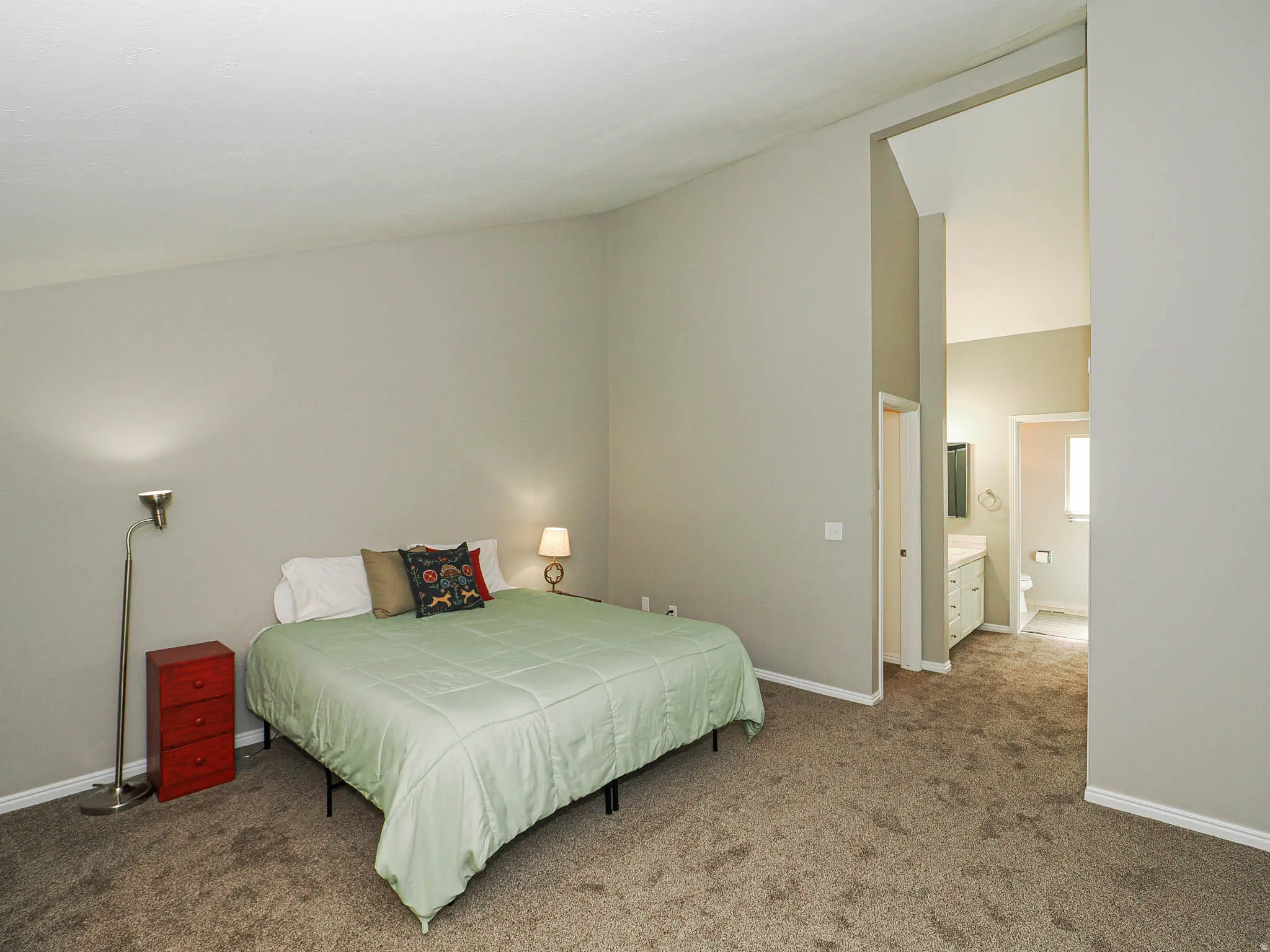Carpeted bedroom featuring neutral wall tones and a vaulted ceiling