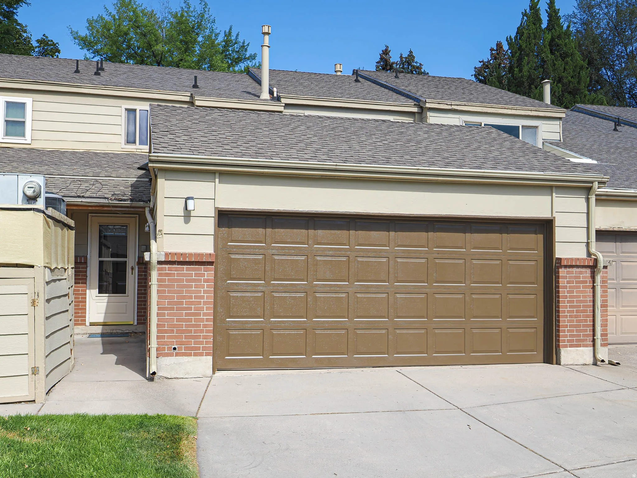 Attached garage with a panel-style door, brick detailing, and an exterior wall light