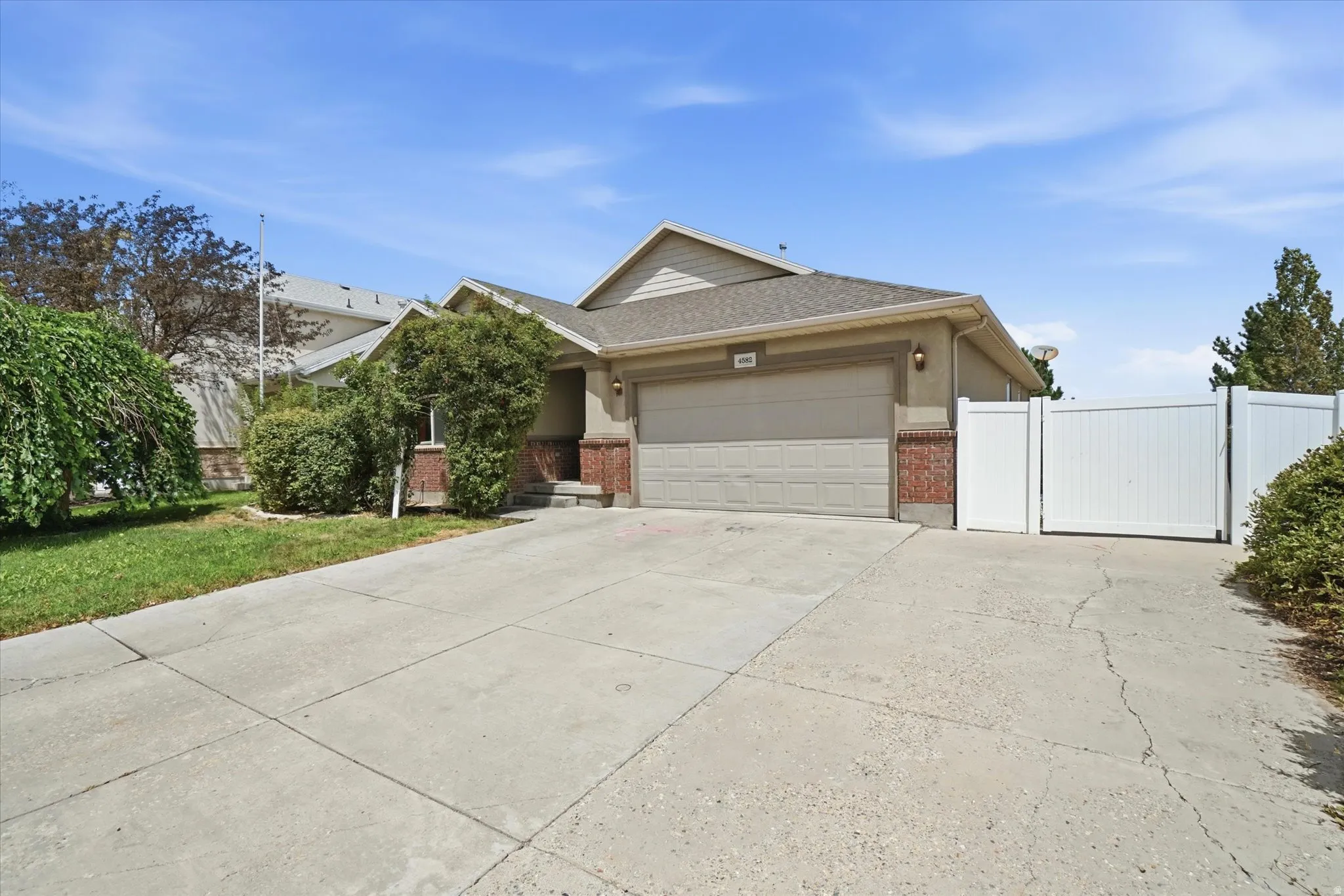 Single-story residence featuring a two-car garage, concrete driveway, and a white vinyl fence