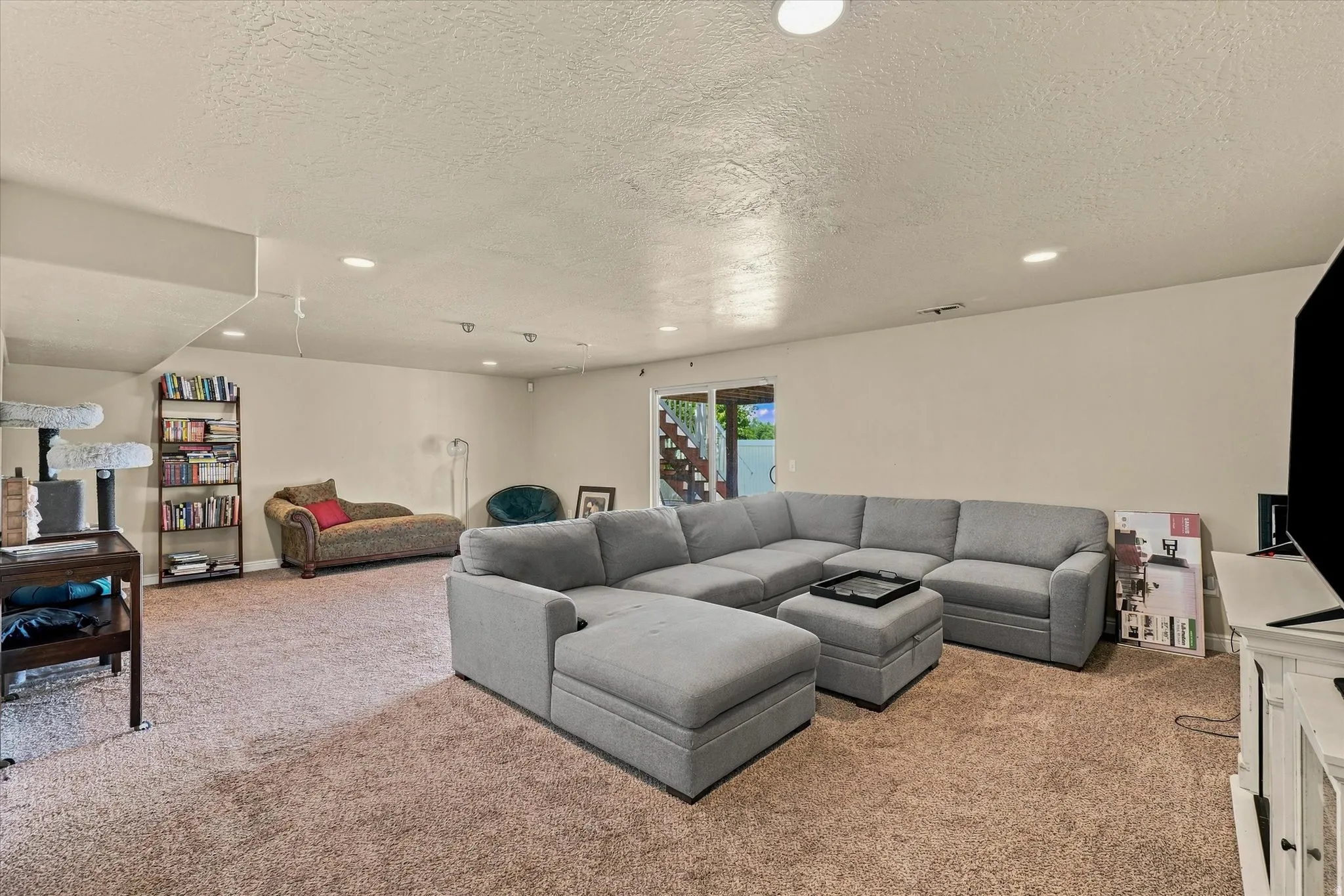 Carpeted recreation room featuring recessed lighting and a built-in bookshelf