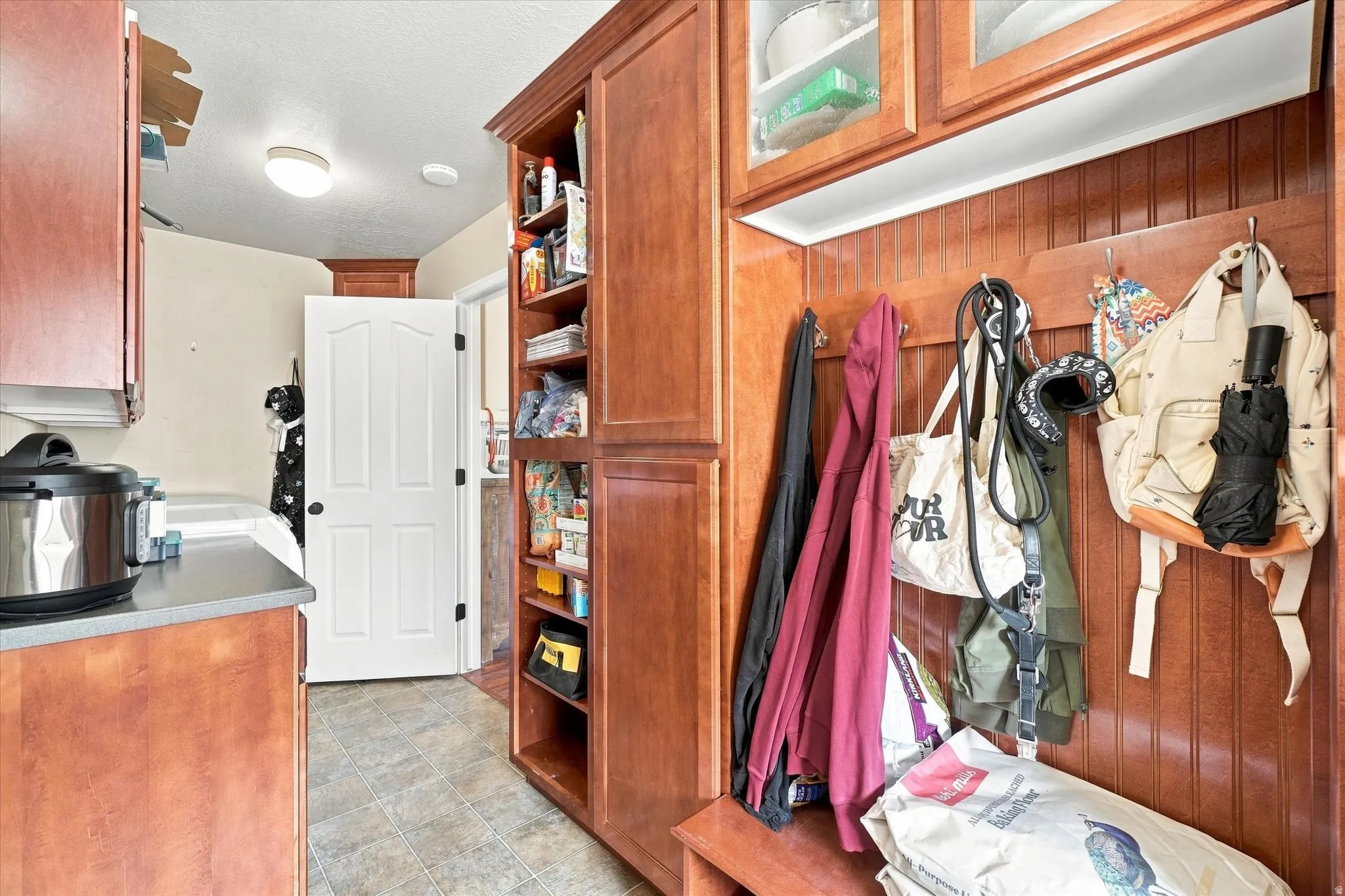 Built-in mudroom features beadboard paneling, upper glass-front cabinetry, and an integrated bench