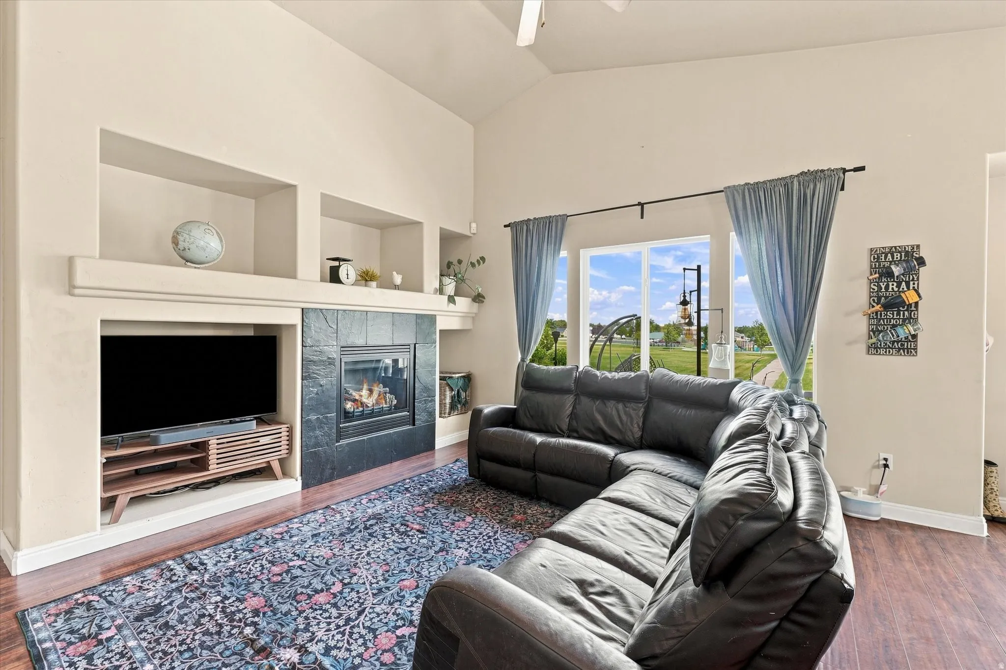 Living room featuring a fireplace with a black tile surround, an integrated media niche, and wood-finish flooring