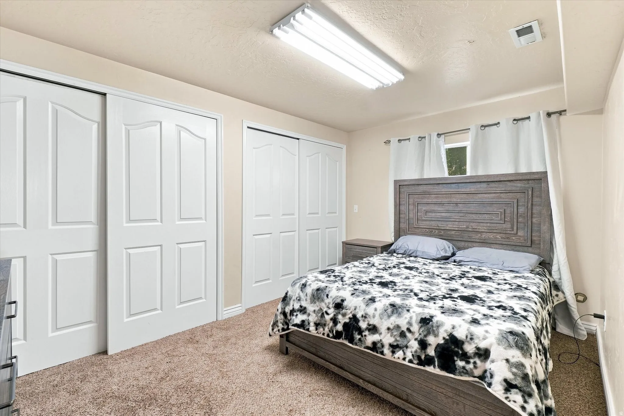 Spacious bedroom #4 featuring multiple bi-fold closet doors, neutral wall paint, and a textured carpet