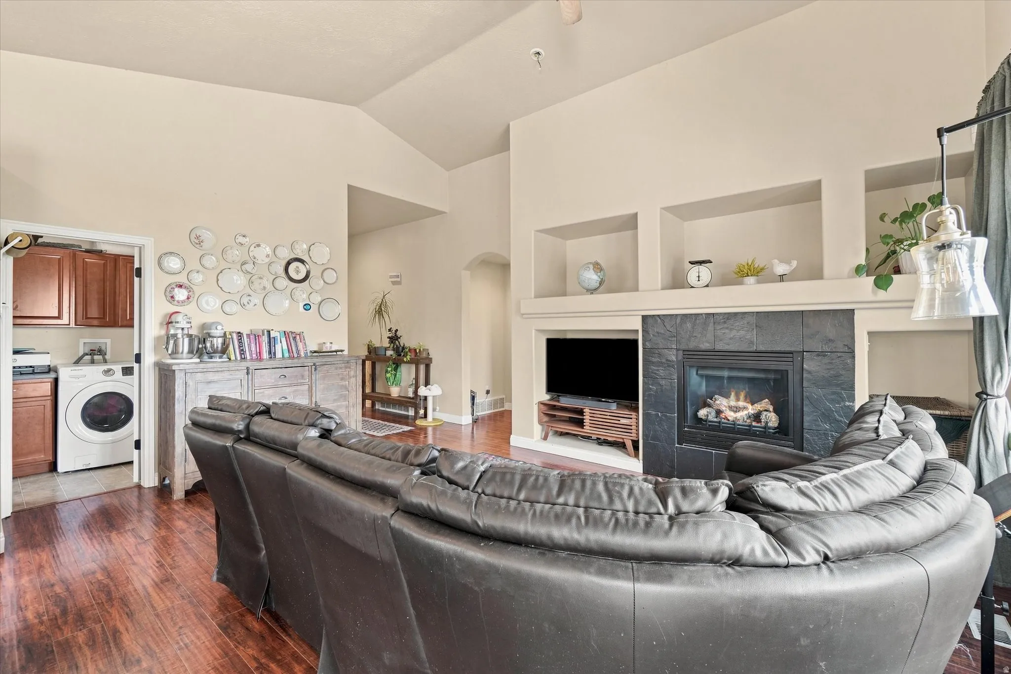 Vaulted ceiling living area featuring wood-finish flooring