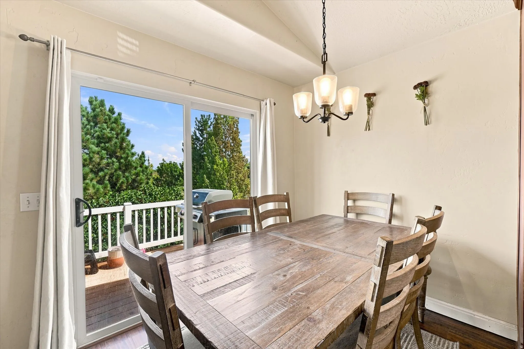 Dining area featuring a contemporary chandelier, wood-finish flooring, and direct access to an outdoor deck