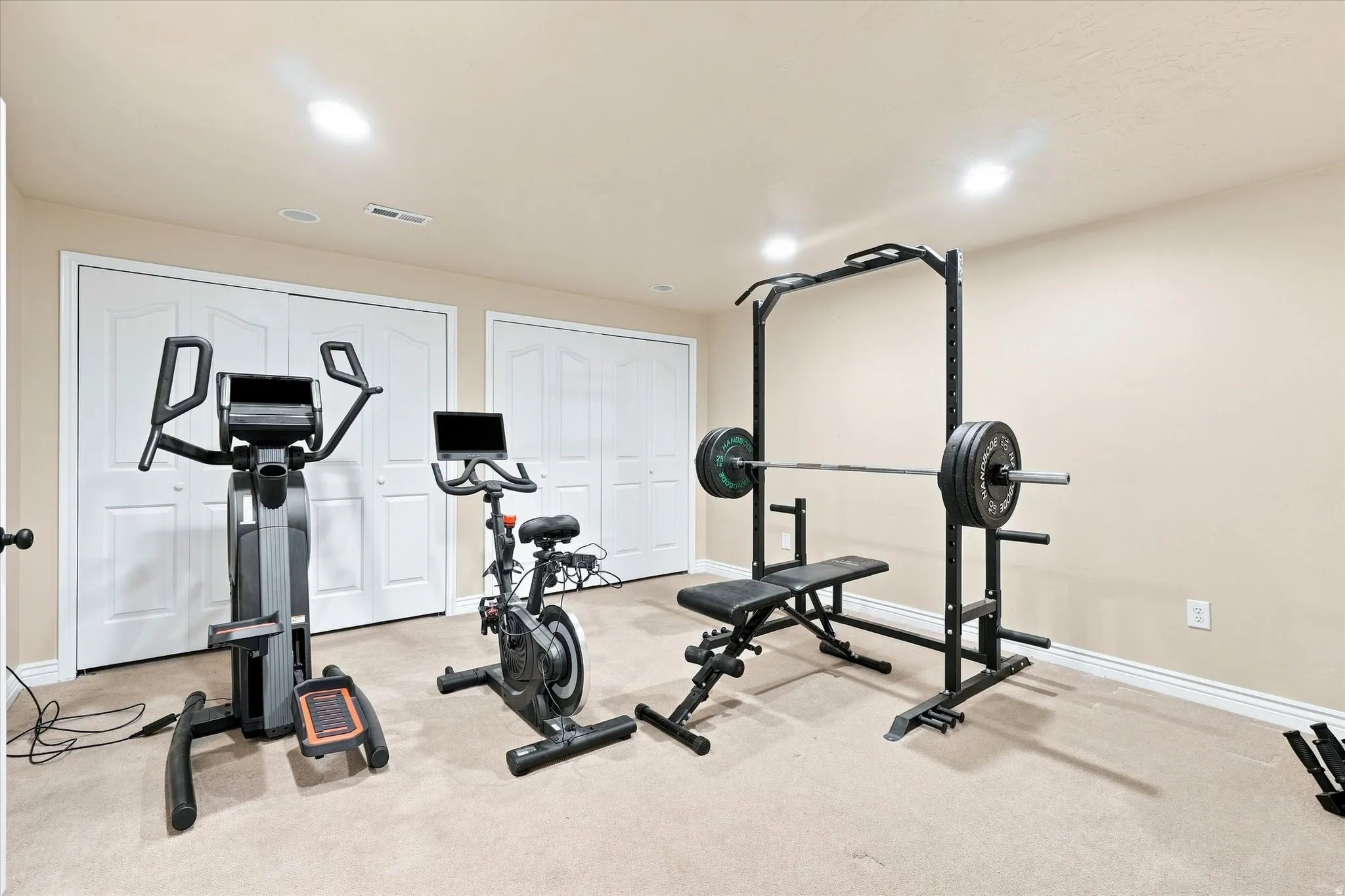 Bonus room featuring recessed lighting, a neutral wall color, white baseboards, and two sets of bi-fold closet doors