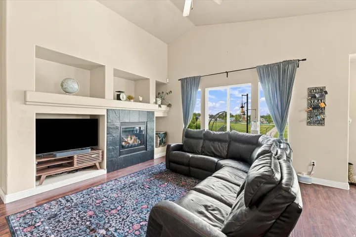Living room featuring a fireplace with a black tile surround, an integrated media niche, and wood-finish flooring