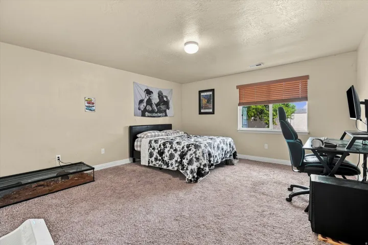Bedroom #5 featuring neutral-toned walls, a single window with horizontal blinds, and an overhead flush-mount light fixture