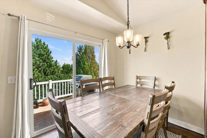 Dining area featuring a contemporary chandelier, wood-finish flooring, and direct access to an outdoor deck