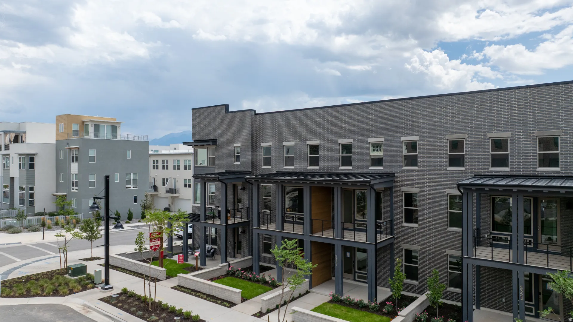 Modern multi-story building featuring a dark gray brick facade and contrasting black window frames