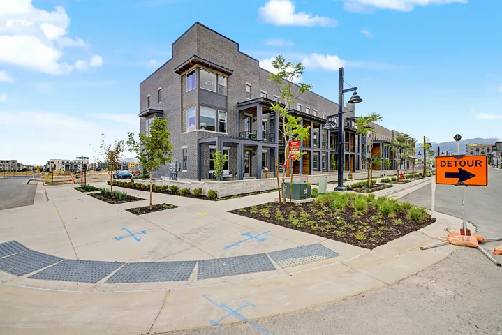 Contemporary multi-story townhome featuring a dark brick facade and multiple window styles