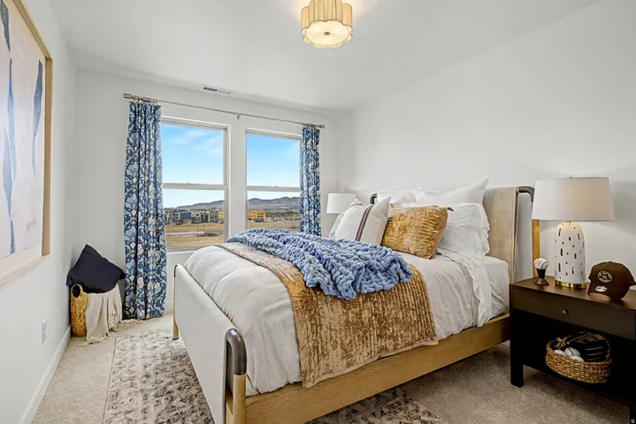 Bright bedroom featuring two large windows, neutral-toned walls, and plush carpeting