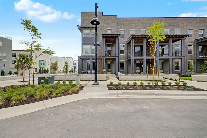 Contemporary townhome-style residences featuring dark brick facades, multiple private balconies with metal railings, and decorative pergolas