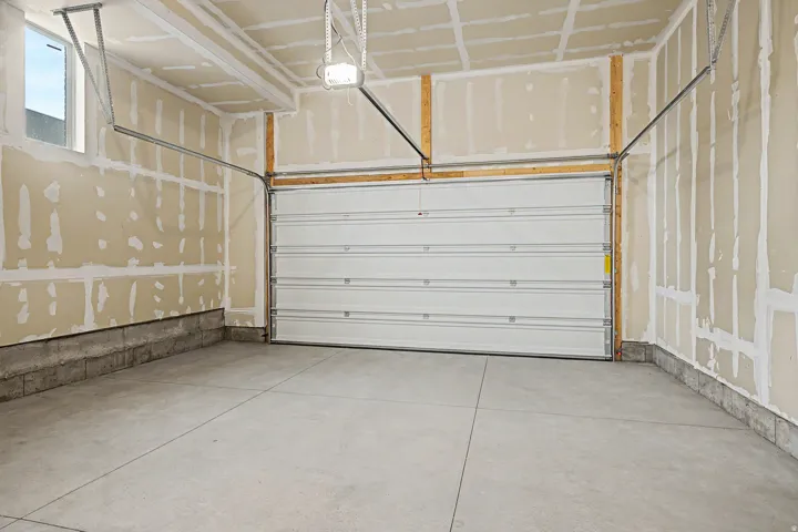 Spacious garage with an automatic overhead door, concrete flooring, and exposed framing