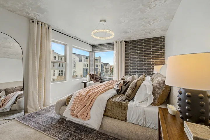 Bedroom featuring a textured accent wall and multiple windows