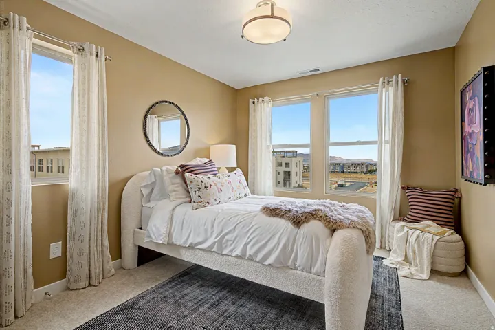 Bedroom featuring warm neutral wall tones and light-colored carpeting