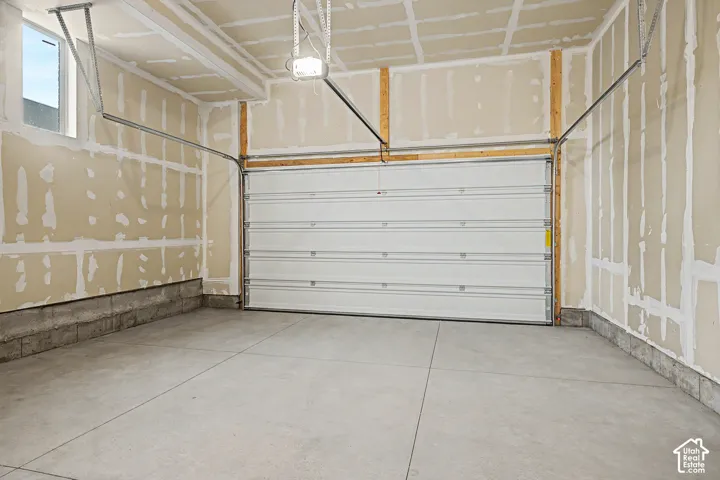 Spacious garage with an automatic overhead door, concrete flooring, and exposed framing
