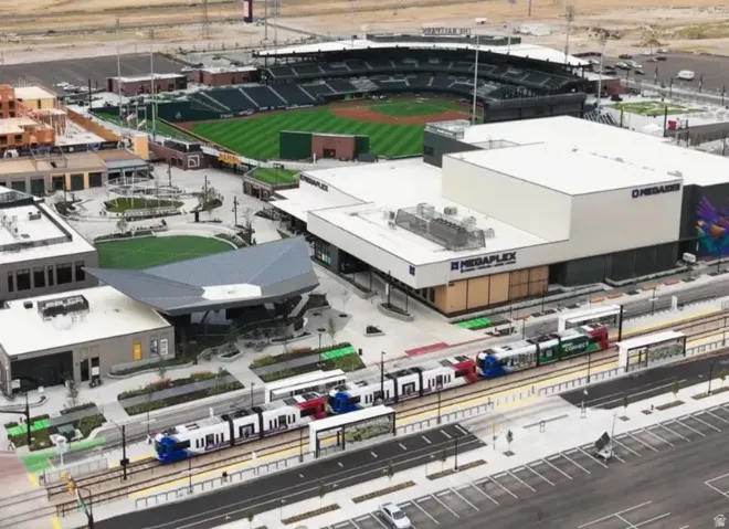 Modern development featuring a baseball stadium, commercial buildings, and a light rail station