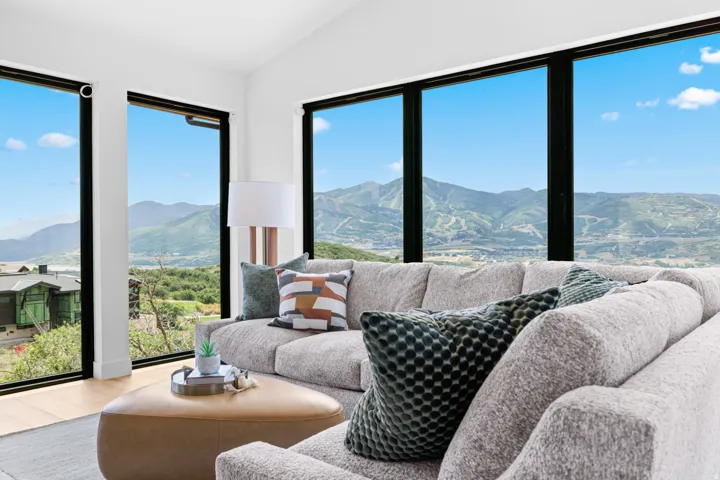 Living area featuring expansive windows with black frames, showcasing mountain and distant water scenery