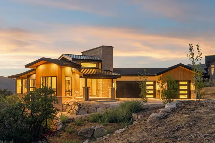 Modern architectural design featuring prominent wood-finish siding, stone accents, and a dark metal roof