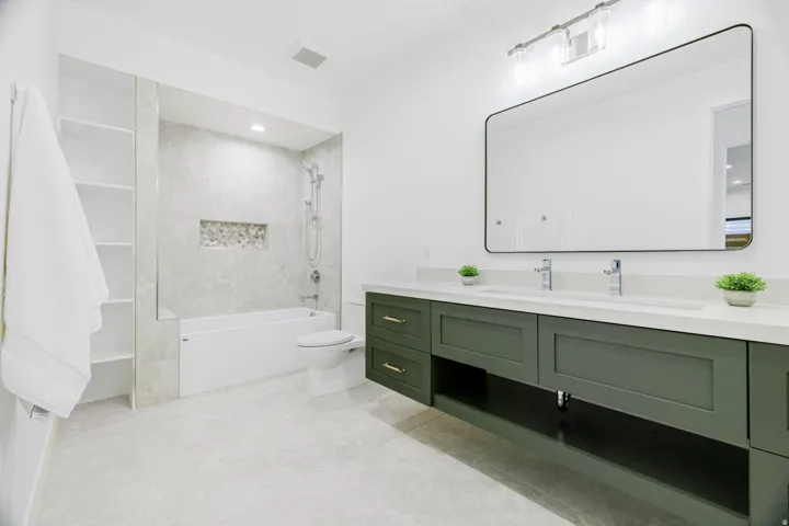 Double vanity with a light countertop and dark green cabinetry
