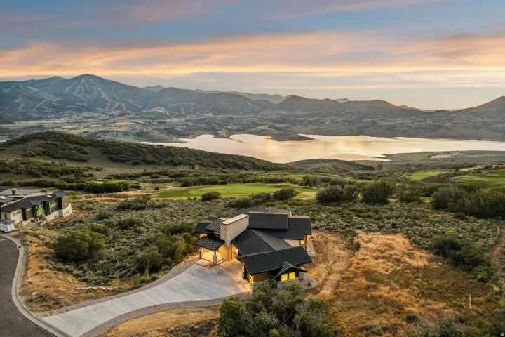Custom residence featuring a dark-toned roof, light-toned exterior walls, and a prominent stone chimney