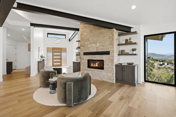 Open-concept living space with a stone-clad fireplace and integrated shelving