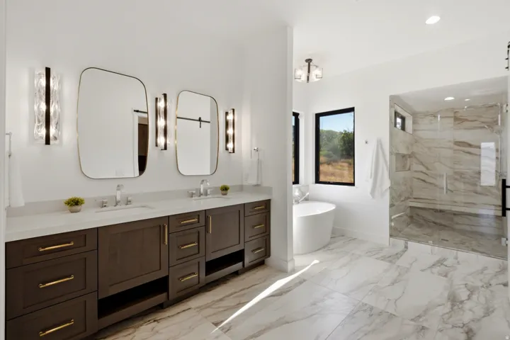 Dual vanity with dark wood-finish cabinetry, gold-tone hardware, and rectangular mirrors