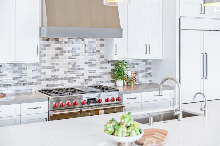 Gourmet kitchen featuring a professional-grade range, stainless steel hood, and full-height mosaic tile backsplash
