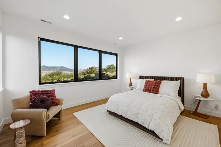 Expansive windows with black framing, wood-finish flooring, recessed lighting, white walls, and white trim