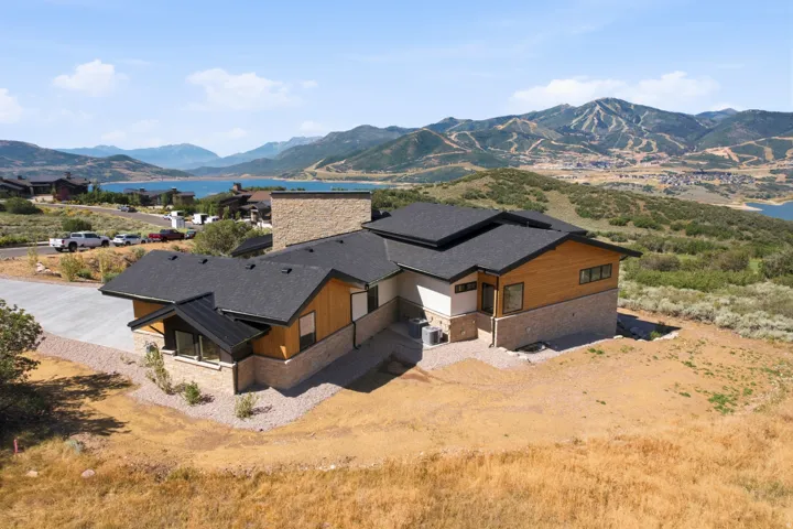 Modern architectural residence featuring multiple rooflines, stone and wood-panel exterior accents, and expansive windows