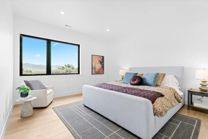 Bright room featuring a large window with black framing, light wood-finish flooring, recessed lighting, and white walls
