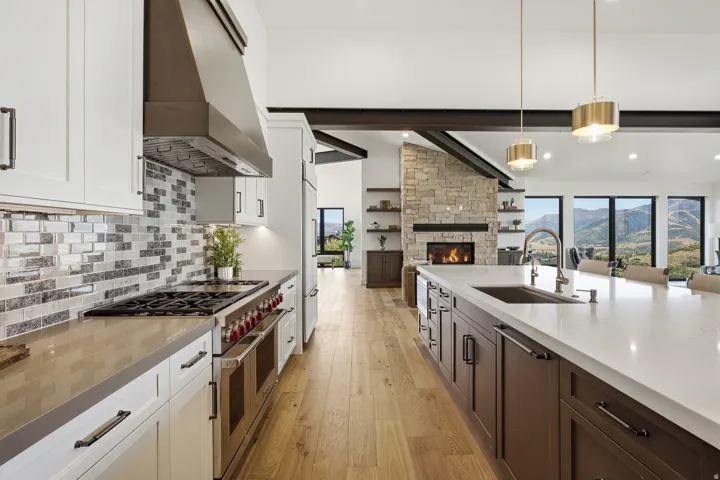 Gourmet kitchen featuring a large island with sink, stainless steel appliances, white cabinetry, and wood-finish flooring