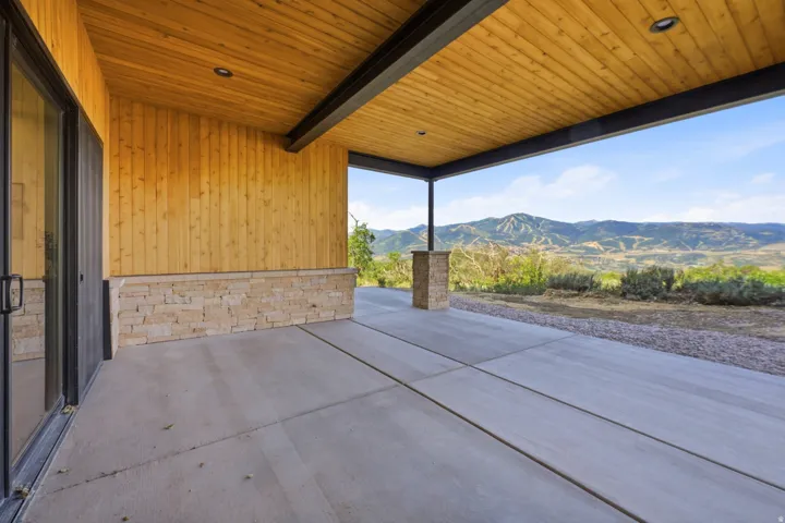 Expansive covered patio featuring a wood-panel ceiling, recessed lighting, and a durable concrete surface