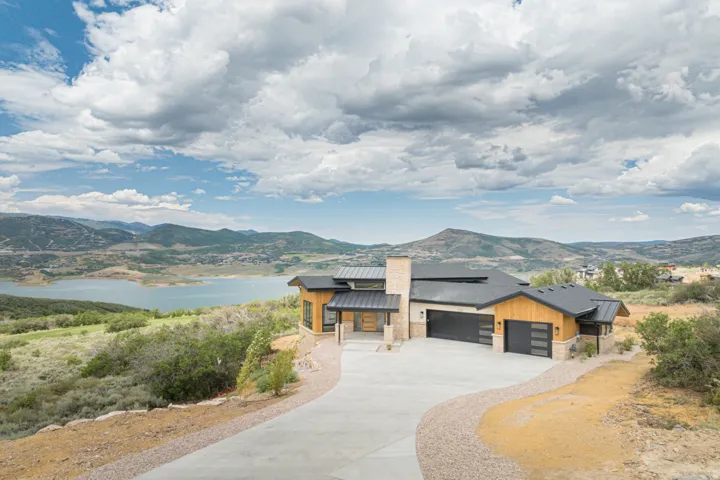 Contemporary residence featuring a multi-tone exterior with wood paneling, stone accents, and a dark roof