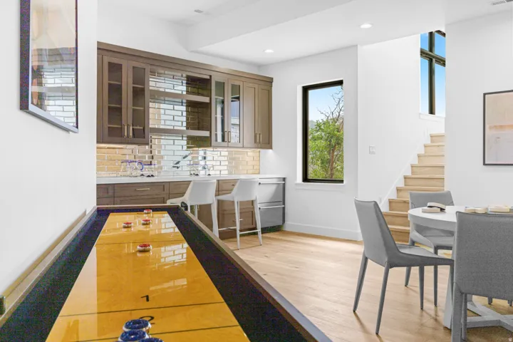 Entertainment area featuring a wet bar with shaker-style cabinetry, a brick-patterned metallic backsplash, and a built-in beverage refrigerator